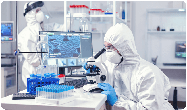 Scientist in lab studying vaccines under a microscope